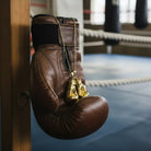 Tyrona gold stainless steel boxing glove pendant necklace symbolizing strength and resilience.