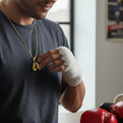 Tyronea gold double boxing glove pendant necklace, crafted from stainless steel with 18K gold bonding.
